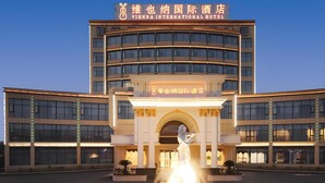Un hotel con entrada central, una fuente y varios pisos.