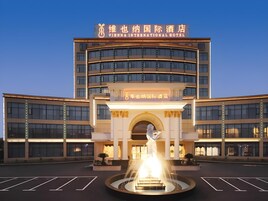 Un hotel con entrada central, una fuente y varios pisos.