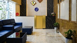 Zona de recepción de un hotel con un sofá, un mostrador y una planta.