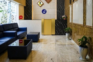 A hotel reception area with a sofa, a reception desk, and a plant. - Zip By Spree Hotels Purple Orchid (Bengaluru)