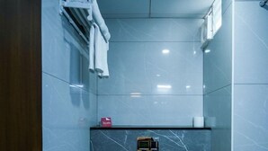 Un baño pequeño con inodoro, toallero, cesto de basura y un estante con artículos de aseo.