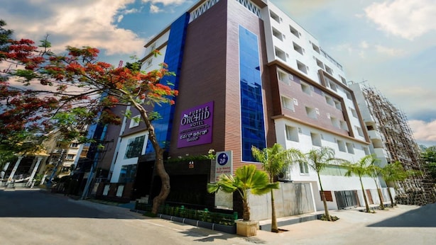 Un hotel con un llamativo letrero morado, fachada moderna y cielo despejado.