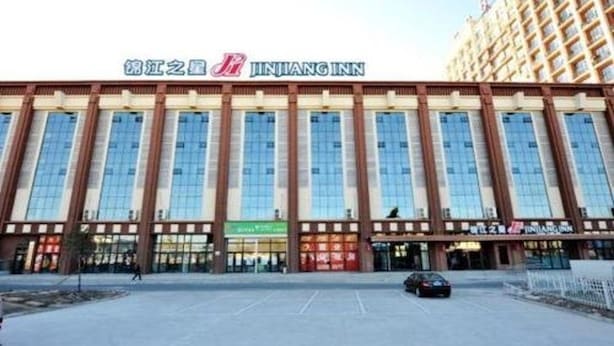 A JINJIANG INN hotel with a modern facade, large windows, and a parking lot in front. - Jinjiang Inn (Daqing)