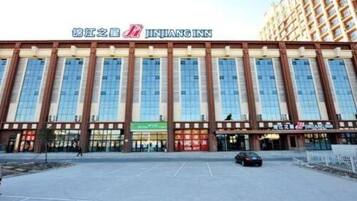 A JINJIANG INN hotel with a modern facade, large windows, and a parking lot in front.