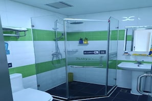 Kylpyhuone, jossa on lasiseinällä varustettu suihku, pesuallas ja wc.