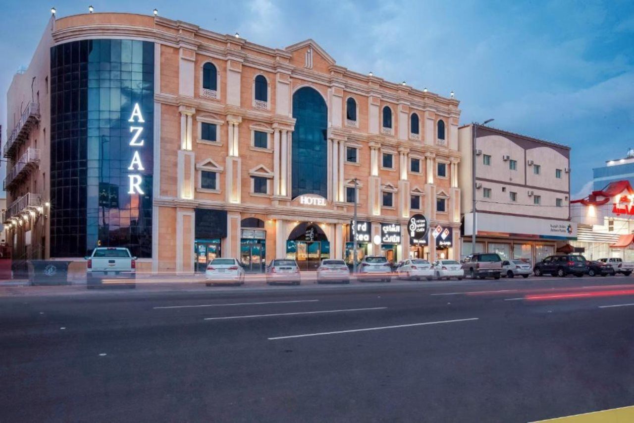 A hotel with a prominent 'AZAR' sign, multiple stories, and a modern glass facade.