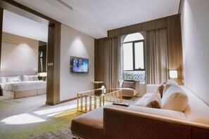 A hotel room with a bed, a sofa, a TV, and a window with curtains. - Azar Hotel Ahad Rafidah (Ahad Rafidah)