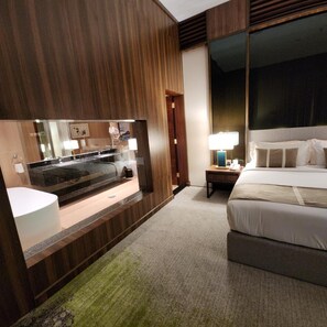 A hotel room with a large bed, a bedside table with a lamp, a mirror, and a view of the outside. - Azar Hotel Ahad Rafidah (Ahad Rafidah)