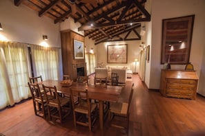 A dining area with a wooden table and chairs, a fireplace, and a map on the wall.