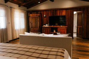A bedroom with a bed, a television, a clock, and wooden paneling.
