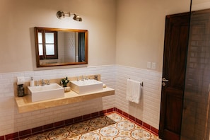 Un baño con dos lavamanos, un espejo y una puerta.