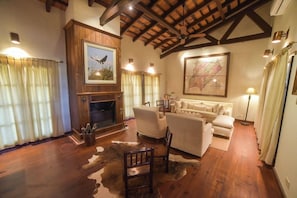 A cozy living room with a fireplace, wooden beams, a map on the wall, and a cowhide rug. - El Transito Hotel Boutique (Concepción)