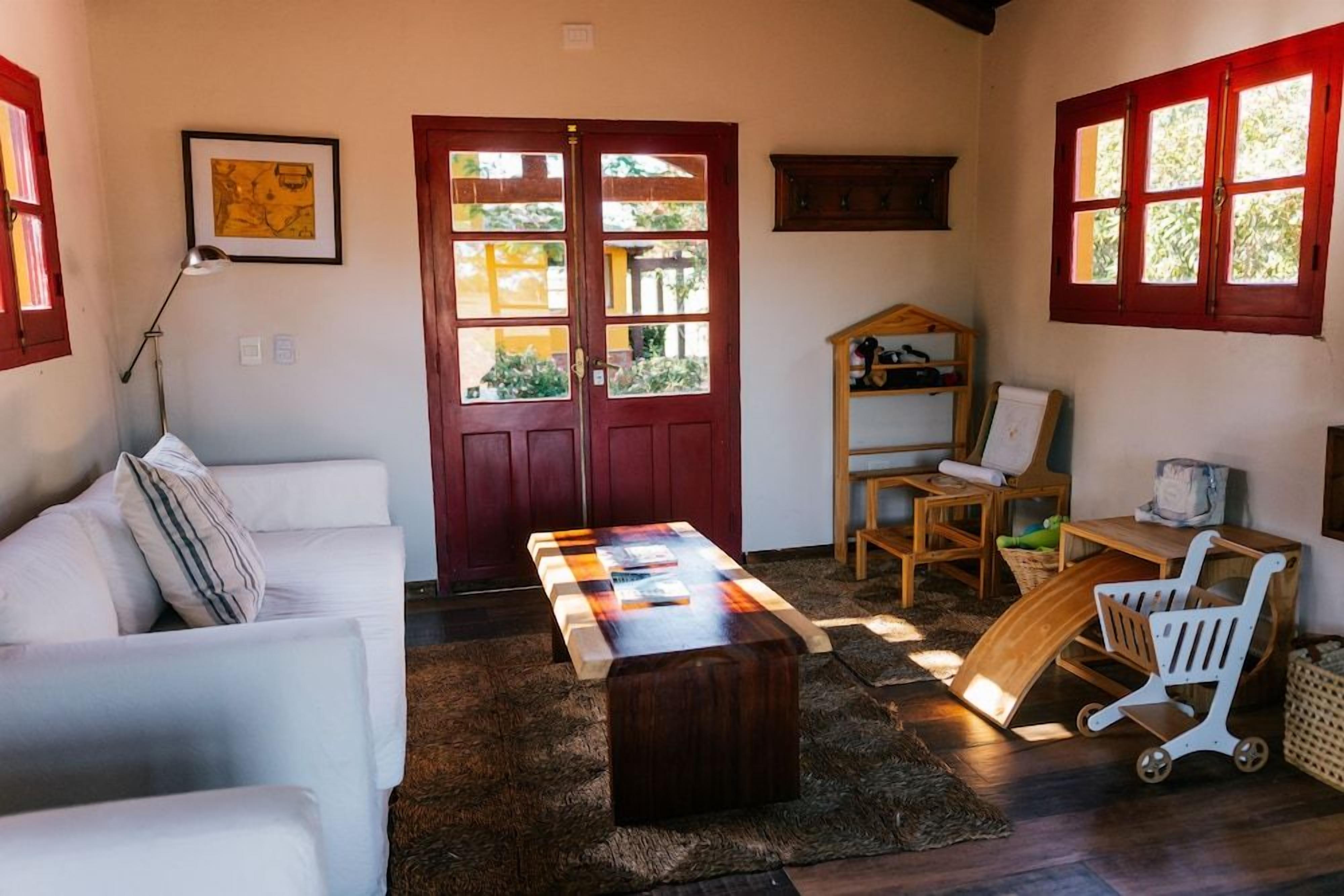 A cozy living room with a white sofa, a wooden coffee table, and a red door with windows.