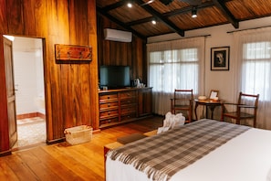 Una habitación de madera con una cama, un televisor, un escritorio y una silla.