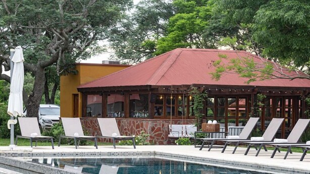 A swimming pool with lounge chairs and a covered seating area. - El Transito Hotel Boutique (Concepción)