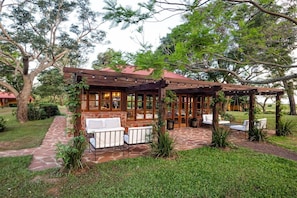 A wooden structure with a covered patio area, stone flooring, and white outdoor furniture. - El Transito Hotel Boutique (Concepción)