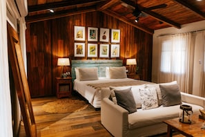A bedroom with a wooden ceiling, a bed with white bedding, a nightstand with a lamp, and a wall with framed bird pictures. - El Transito Hotel Boutique (Concepción)