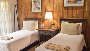 A room with two beds, a nightstand with a lamp, and a painting on the wall. - El Transito Hotel Boutique (Concepción)