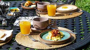 A breakfast setup on an outdoor table with plates of food, glasses of orange juice, and a cup. - El Transito Hotel Boutique (Concepción)