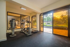 Un gimnasio con equipo de ejercicio y amplias ventanas.