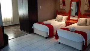 Hotellihuone, jossa on kaksi erillistä sänkyä, vaatekaappi ja peili.