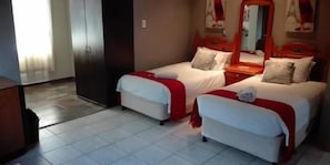 Une chambre d’hôtel avec deux lits simples, une armoire et un miroir.