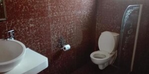 Une salle de bain avec un lavabo blanc, des toilettes et une douche à parois de verre.