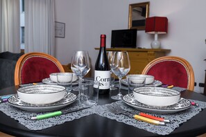 Ein Esszimmertisch mit Tellern, Gläsern und einer Weinflasche, umgeben von Stühlen.