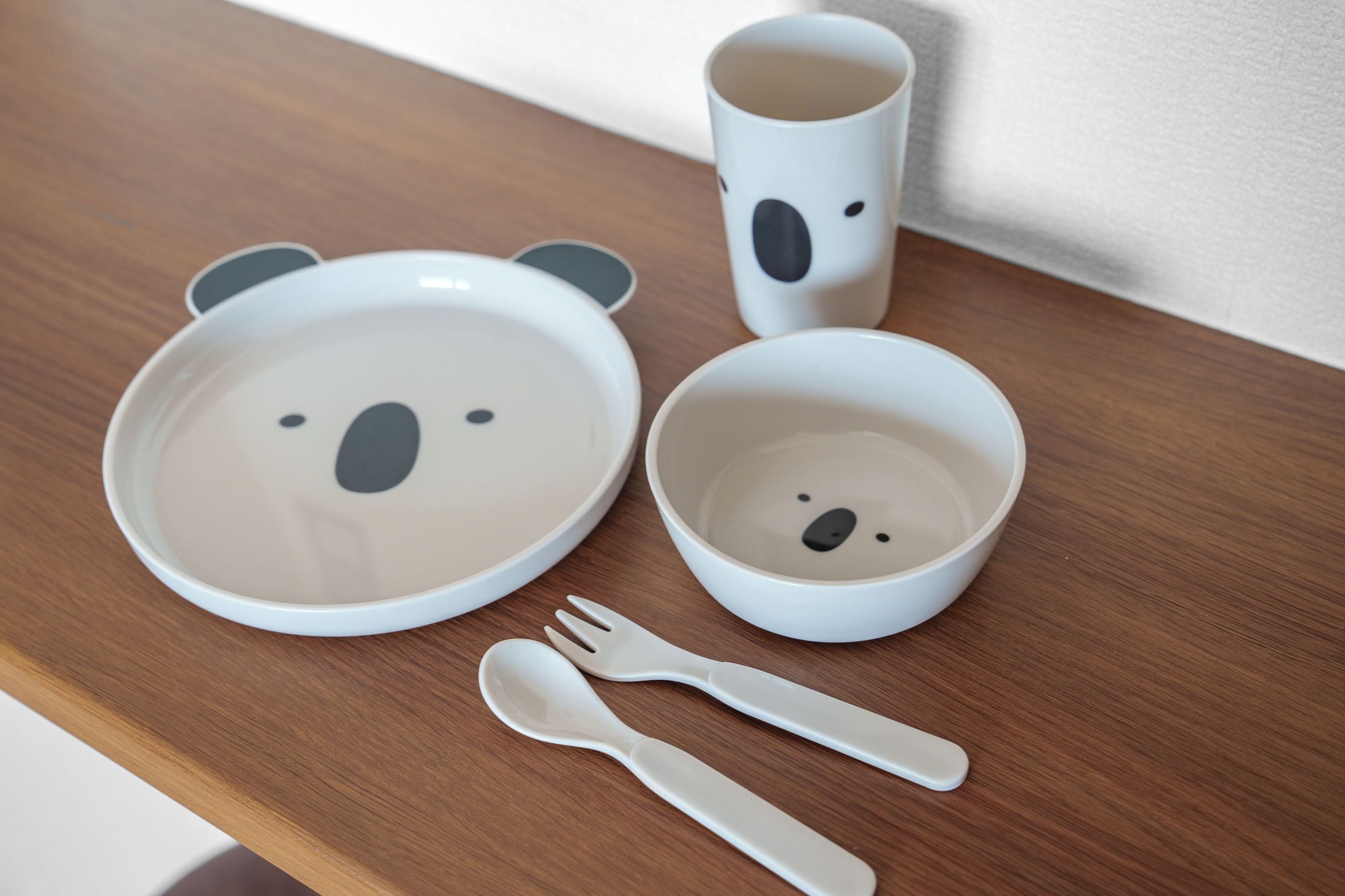 A table with a bear-themed set of cutlery and a cup.