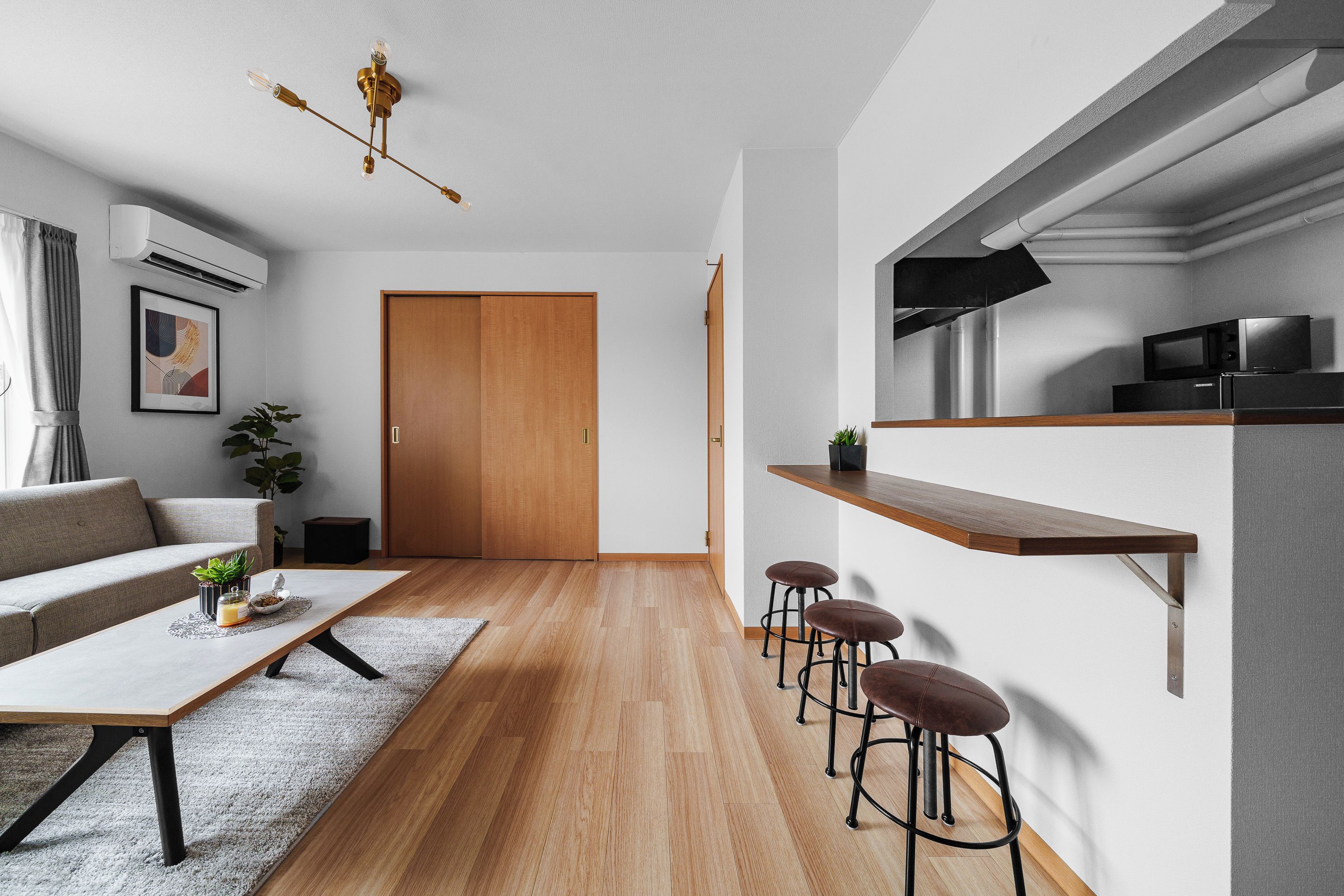 A modern living space with a sofa, coffee table, and bar stools.