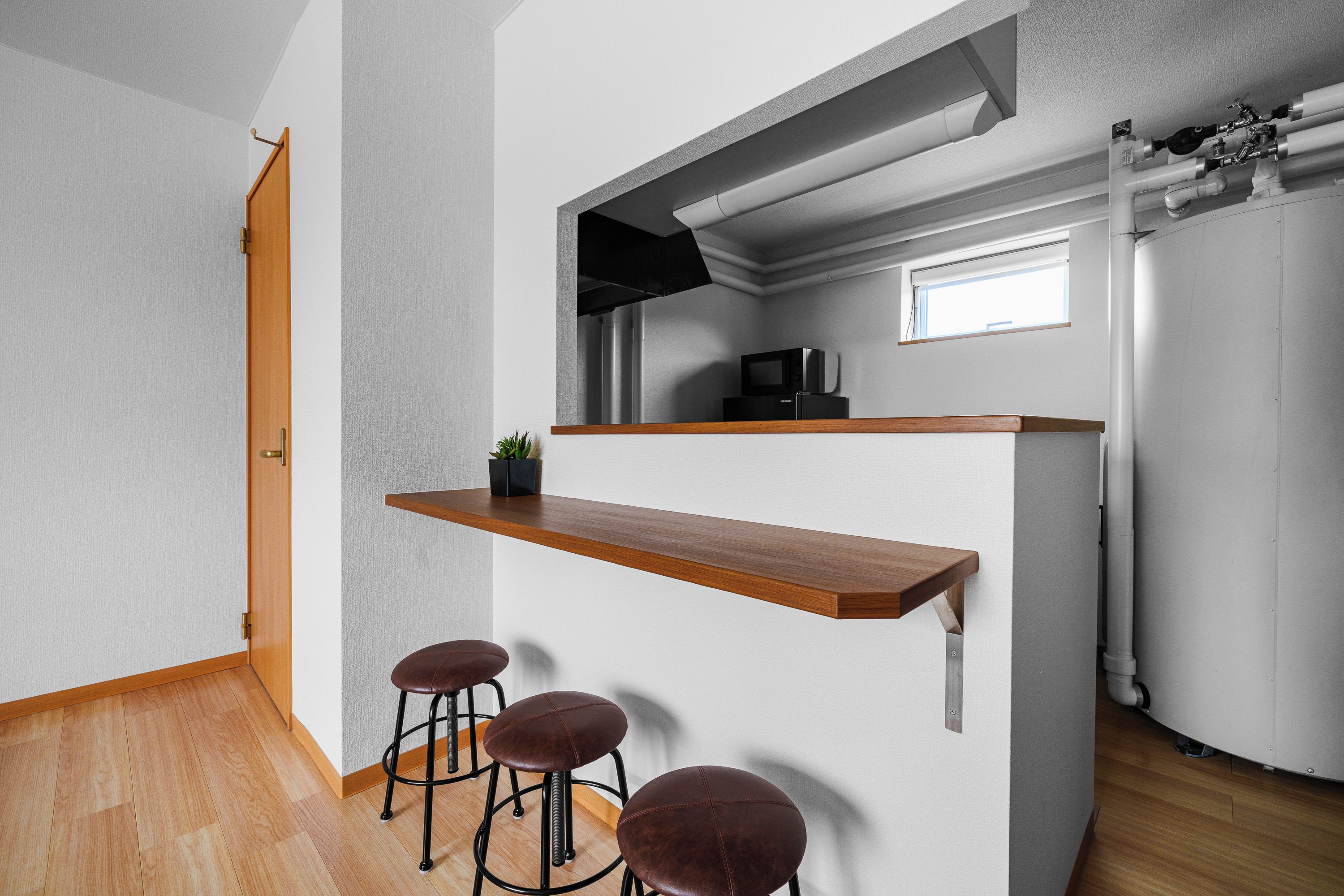 A compact kitchen with a wooden countertop, a microwave, and a small refrigerator.