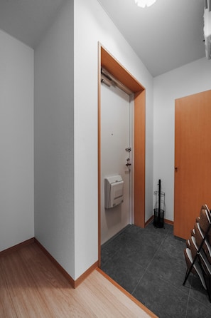 A hallway with a door, a hand dryer, and a rack with items.