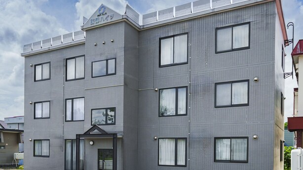 A multi-story building with a tiled facade, a flat roof, and a sign indicating it is a hotel. - SHINTO NEST 202 (Asahikawa)
