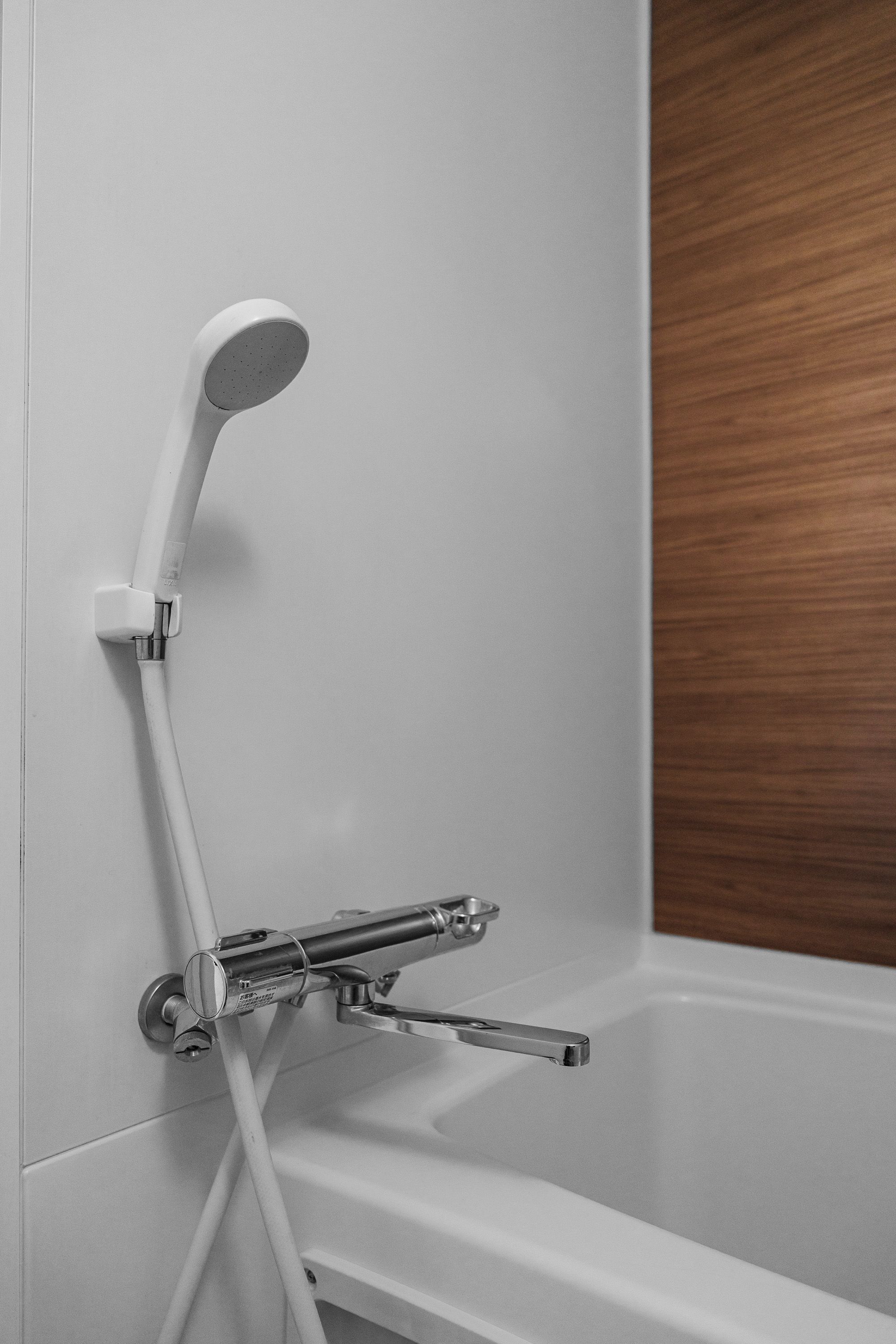 A modern shower with a handheld showerhead and a fixed wall-mounted faucet.