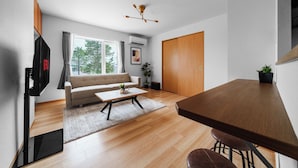 A modern living room with a sofa, coffee table, and a dining area with a table and chairs. - SHINTO NEST 202 (Asahikawa)
