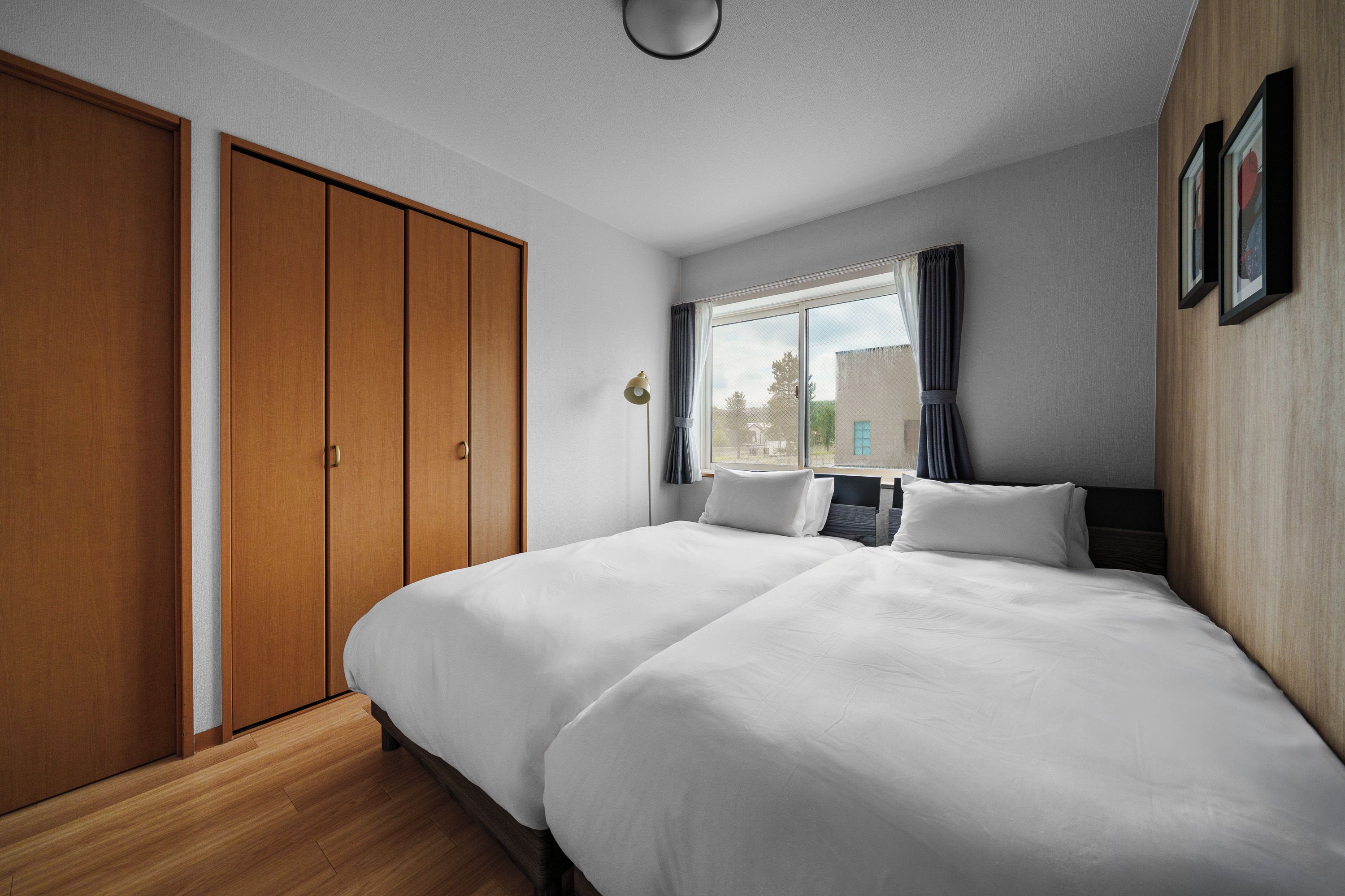 Une chambre d’hôtel avec un grand lit, une armoire, une fenêtre avec des rideaux et une vue sur l’extérieur.