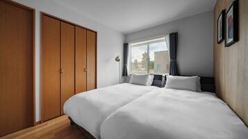 Une chambre d’hôtel avec un grand lit, une armoire, une fenêtre avec des rideaux et une vue sur l’extérieur.