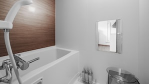 A modern bathroom with a white bathtub, a wooden panel wall, a mirror, and a glass shower chair. - SHINTO NEST 202 (Asahikawa)