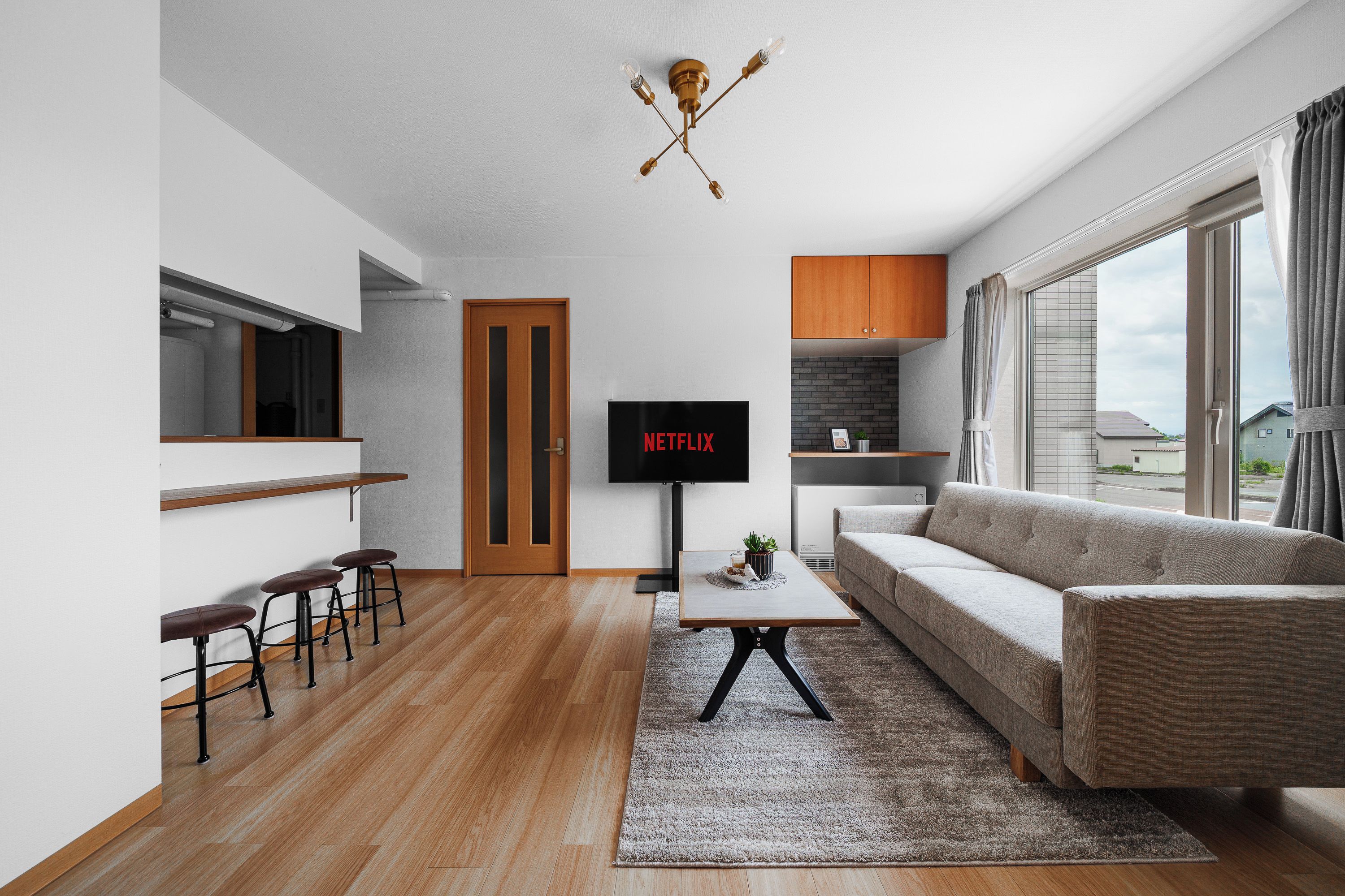 Ein modernes Wohnzimmer mit einer Couch, einem Couchtisch, einem Fernseher und einer Bar mit Hockern.