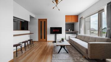 Ein modernes Wohnzimmer mit einer Couch, einem Couchtisch, einem Fernseher und einer Bar mit Hockern.
