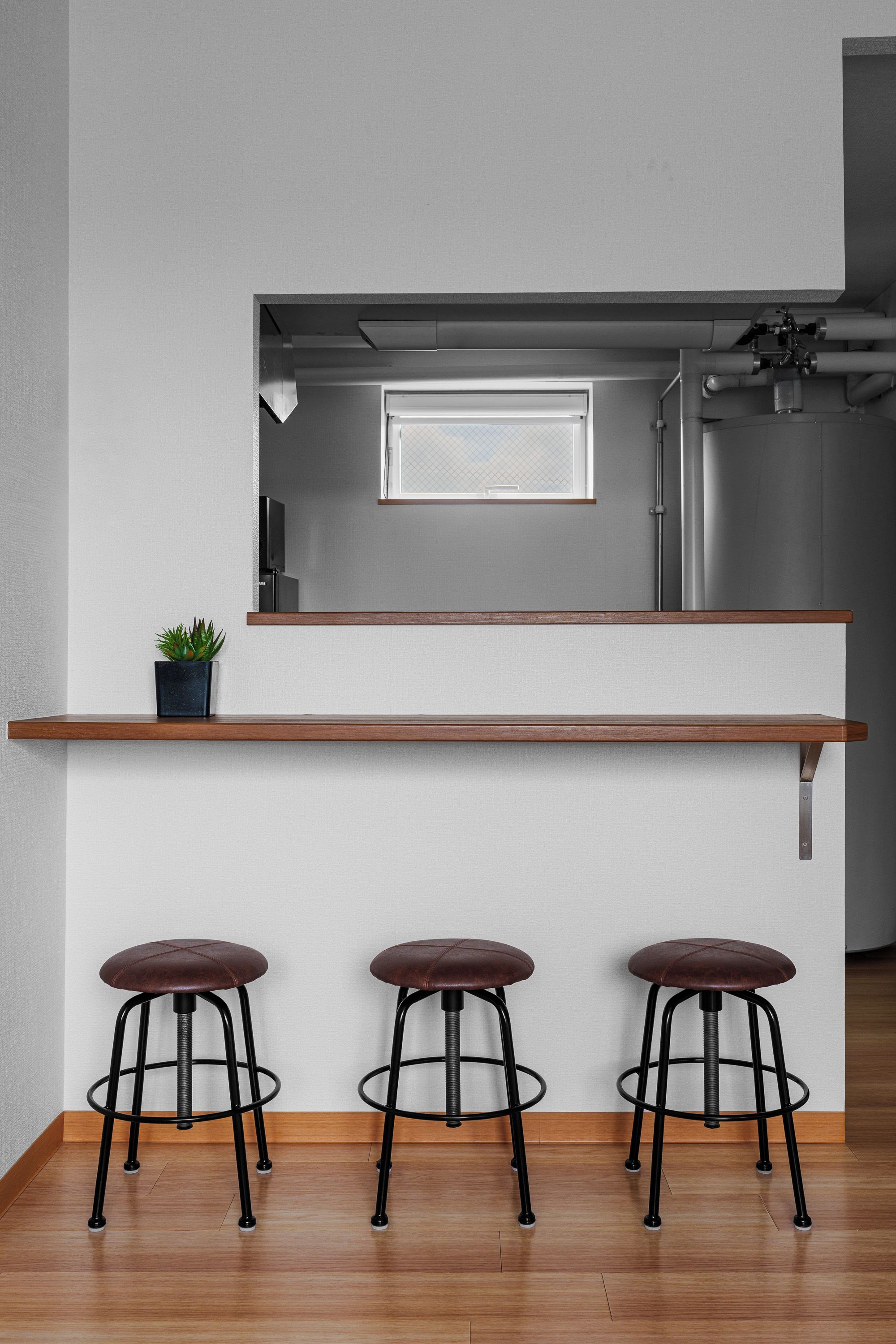 Una cocina con encimera de madera, tres taburetes y una planta en maceta.