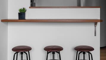 Una cocina con encimera de madera, tres taburetes y una planta en maceta.