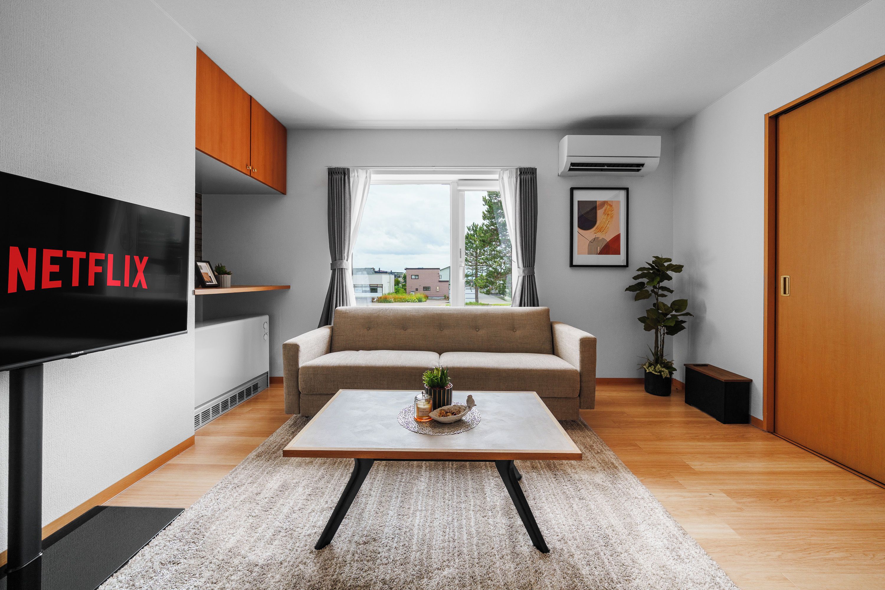 A modern living room with a sofa, a coffee table, a TV, and a view through the window.