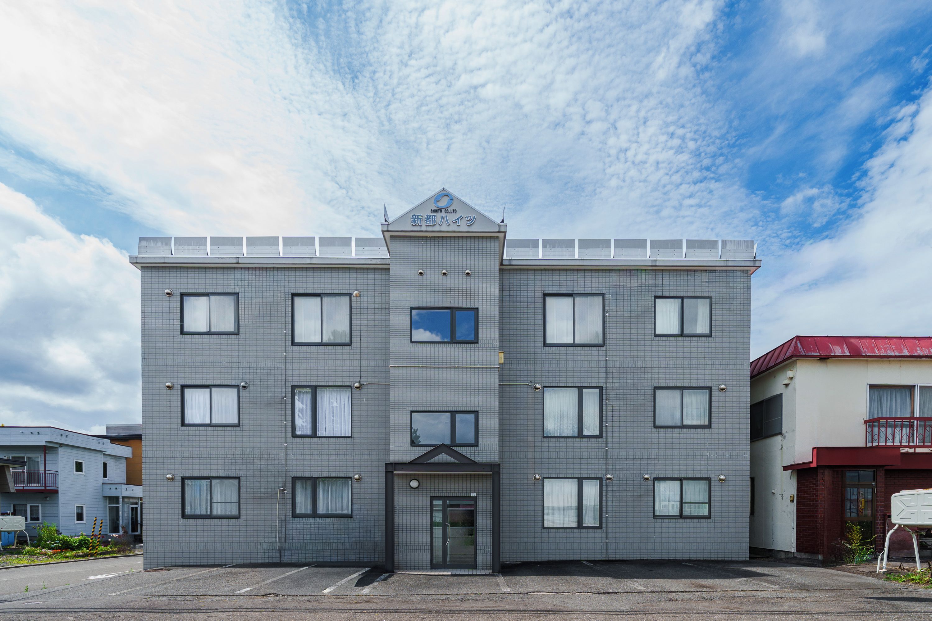 A multi-story building with a symmetrical facade, a central entrance, and a flat roof with solar panels.