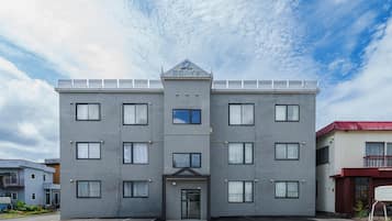A multi-story building with a symmetrical facade, a central entrance, and a flat roof with solar panels.