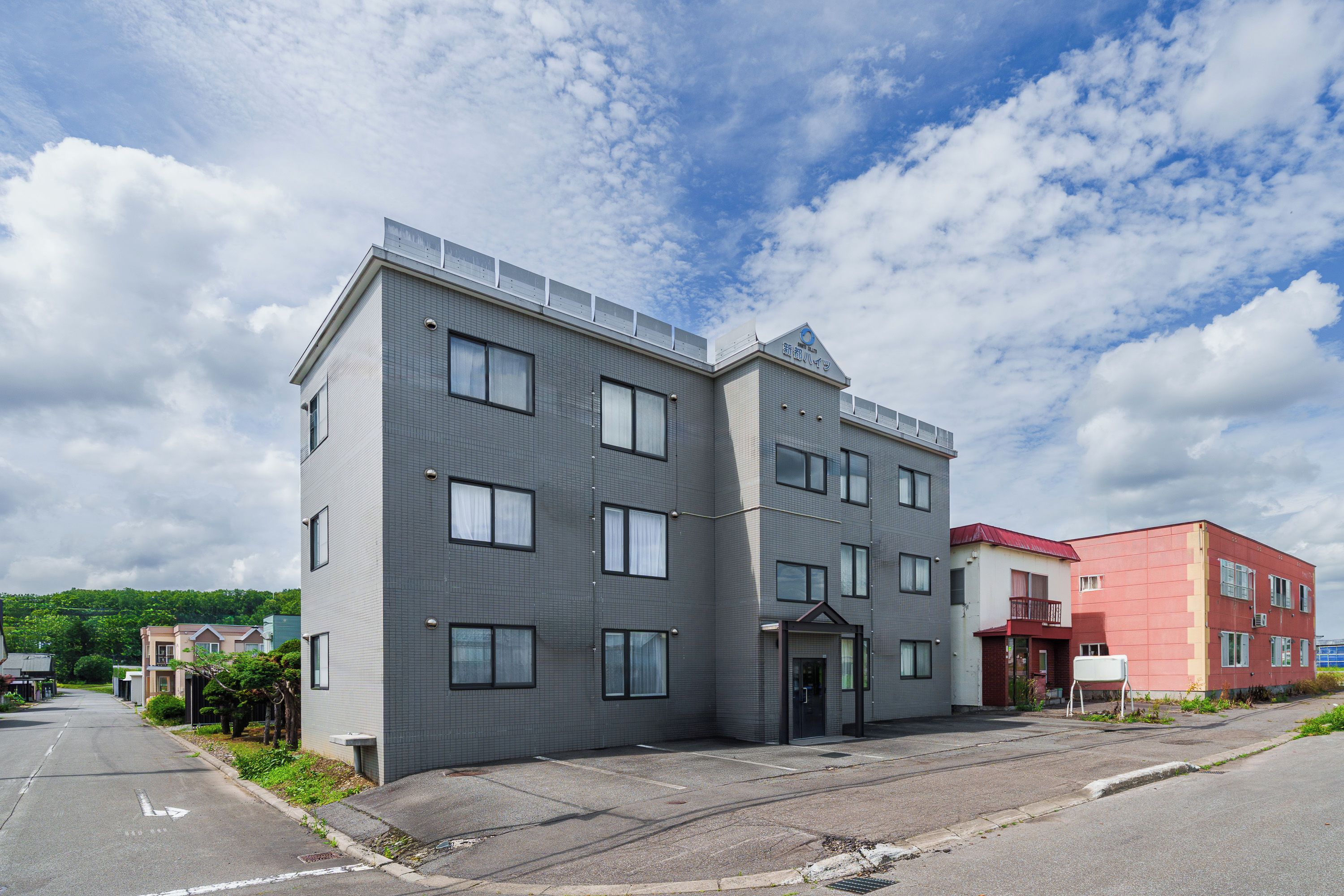 A multi-story building with a flat roof, large windows, and a visible entrance.