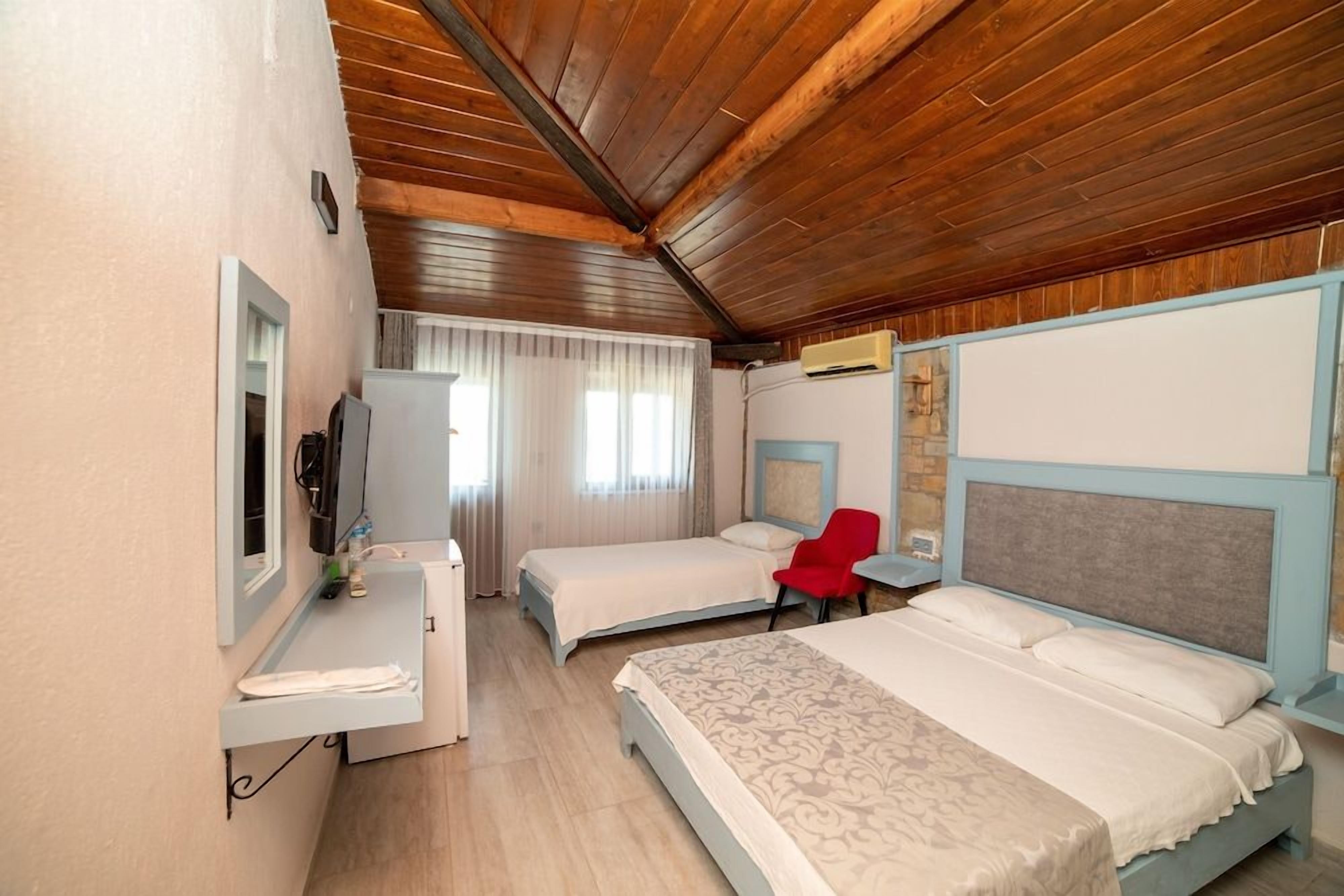 A hotel room with two beds, a desk, a chair, a TV, and a bathroom.