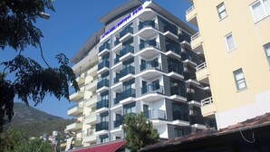 Um hotel com vários andares e varandas, céu claro e uma montanha ao fundo.