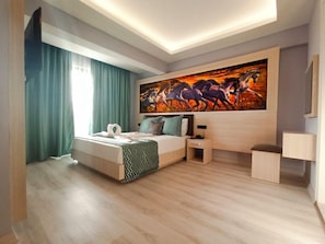Habitación de hotel moderna con una cama, una mesita de noche, un escritorio y un cuadro grande en la pared.