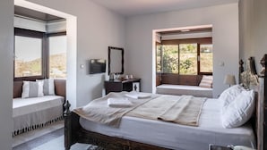 Un dormitorio con una cama grande, dos ventanas, una mesita de noche y un espejo.